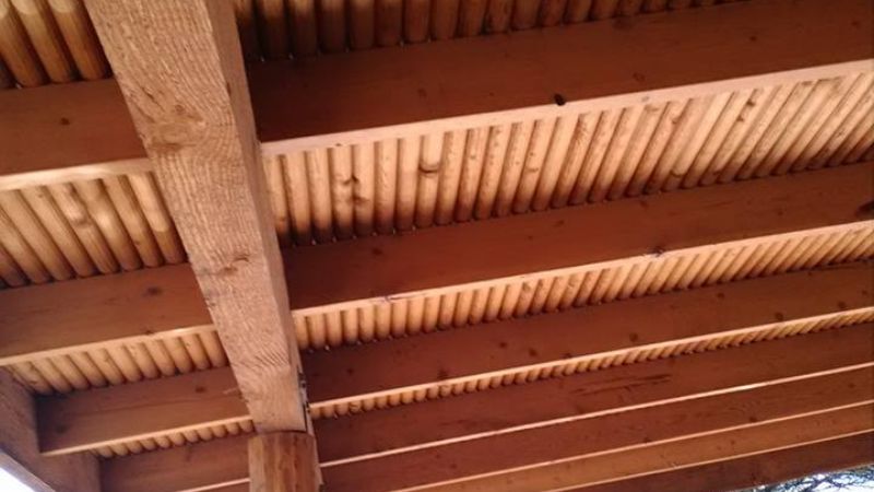 Wooden beams and rafters forming the underside of a rustic wooden structure, likely a patio or gazebo, showcasing a simple yet sturdy construction prepared for an interior painting.