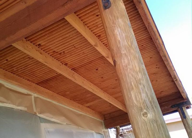 Wooden beams supporting a roof structure with a close-up on the natural wood grain and sturdy construction, prepared for interior painting to enhance their appearance.