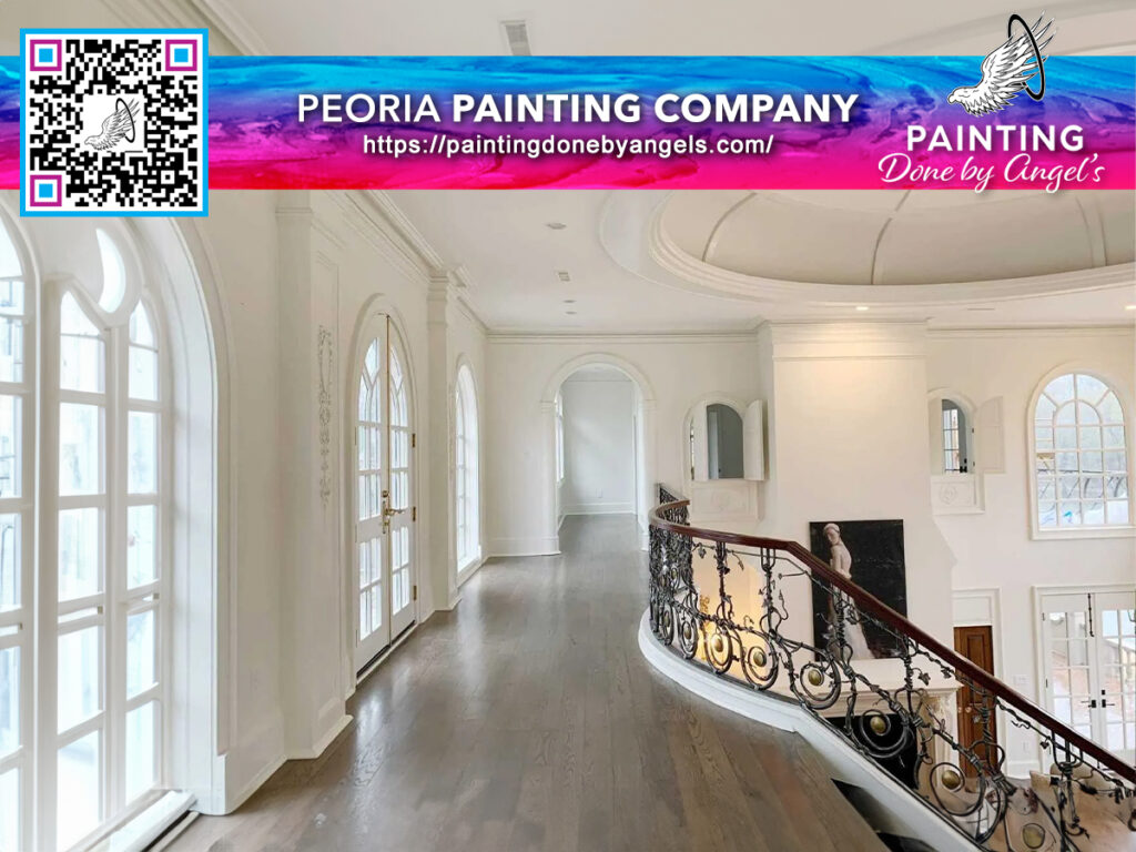 Elegant interior corridor with pristine white walls, arched windows, and a classic wrought iron railing along a polished wooden floor, featuring an advertisement for a painting company specializing in exterior painting and stucco