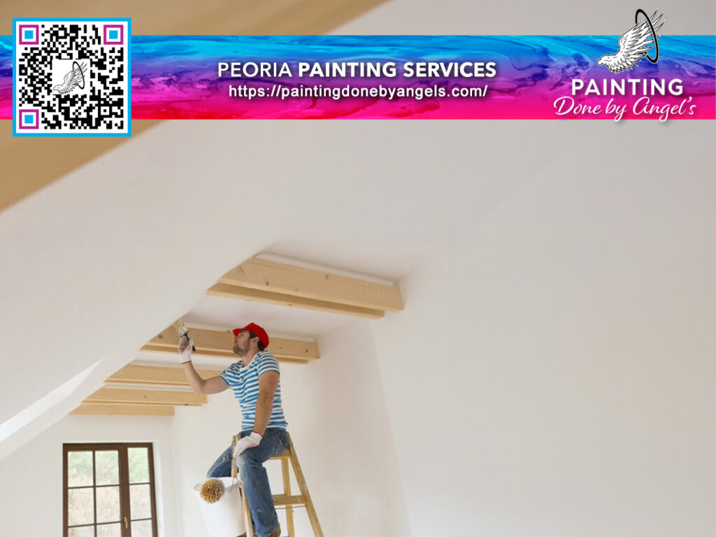 A painter in a red cap and striped shirt on a ladder applying paint to the edge of a ceiling in a room, with an advertisement for Peoria interior painting services above featuring a colorful logo and QR