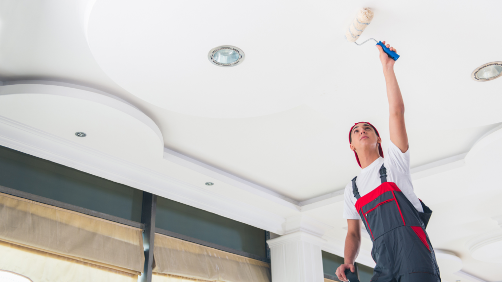 A professional painter from a Painting Company carefully applying a fresh coat of white paint to a ceiling, showing attention to detail and precision.