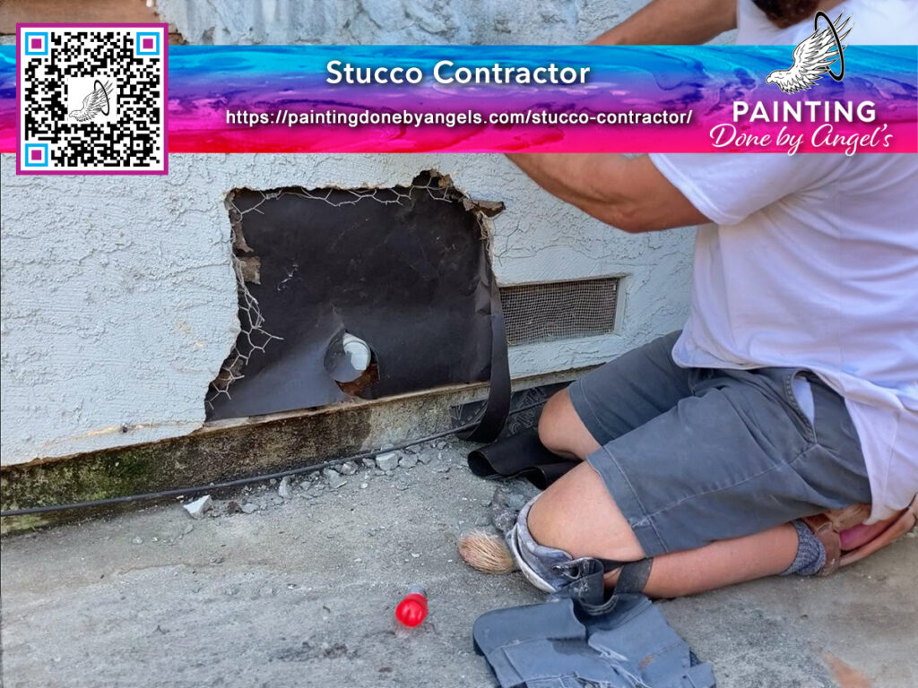 A stucco repair contractor kneels and inspects a large hole in a white external wall, with a business advertisement overlay featuring a QR code and logo.