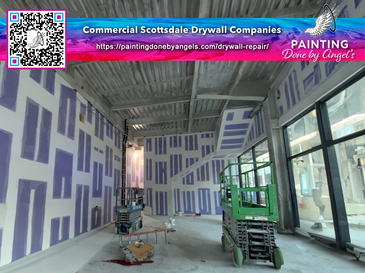 Interior construction in progress: drywall installation, stucco repair, and patchwork underway in an empty commercial space, with tools and machinery on site, and a promotional ad for a Scottsdale dry