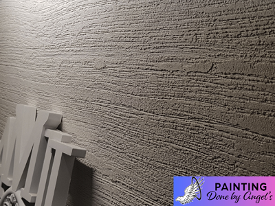 A close-up view of a textured drywall repair with a subtle play of shadows, showcasing the meticulous detail and pattern of the surface finish.