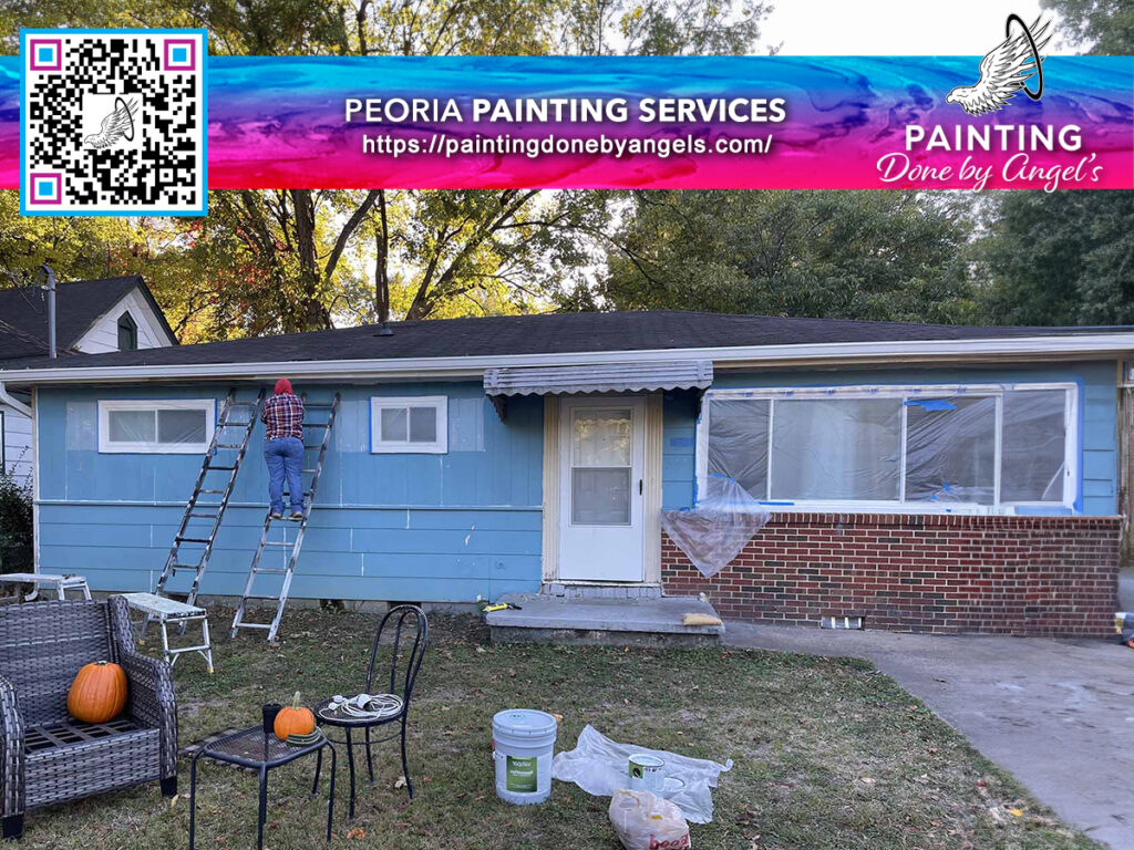 Home renovation in progress with painting services and stucco repair at work, featuring a blue single-story house partially covered with plastic sheeting, a ladder set against the front, and painting supplies scattered on